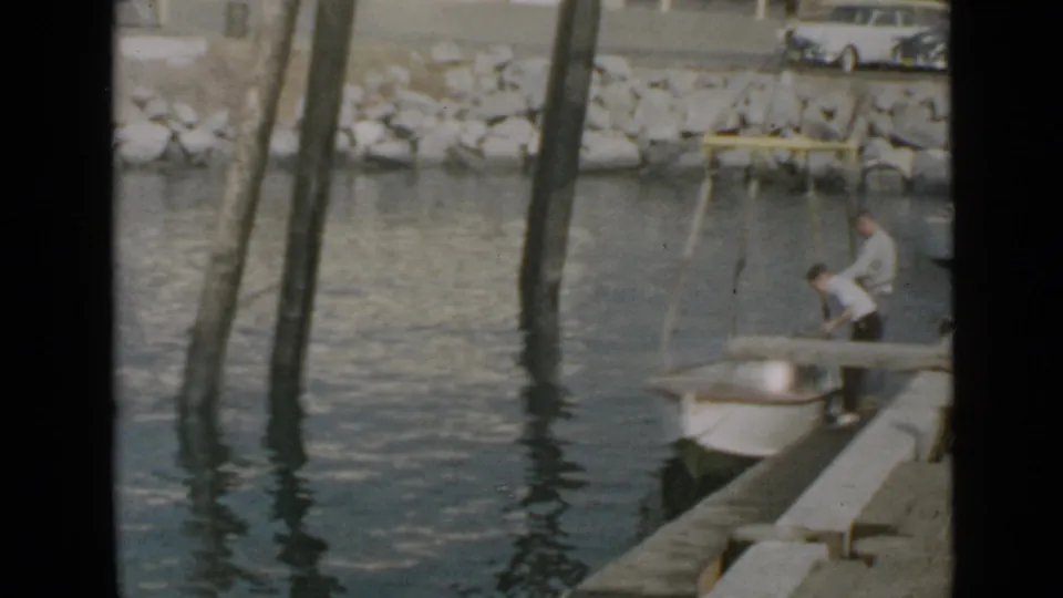 At the end of the brief San Diego boating scene, one man bends over the small boat beside the dock as another remains near the stern.