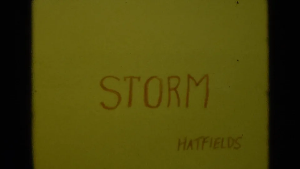 Yellow family-film title card reading STORM with HATFIELDS written below, framed by dark 8mm gate edges.