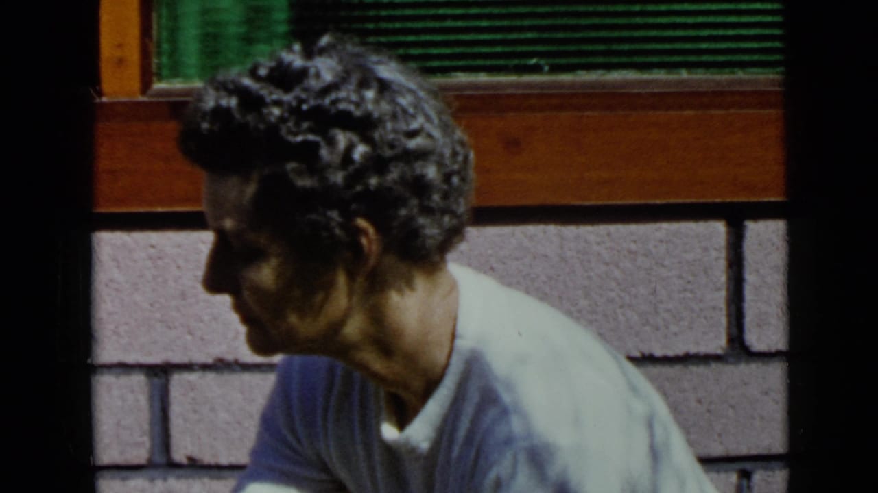 Man in profile looks downward beside the masonry wall and wood trim.