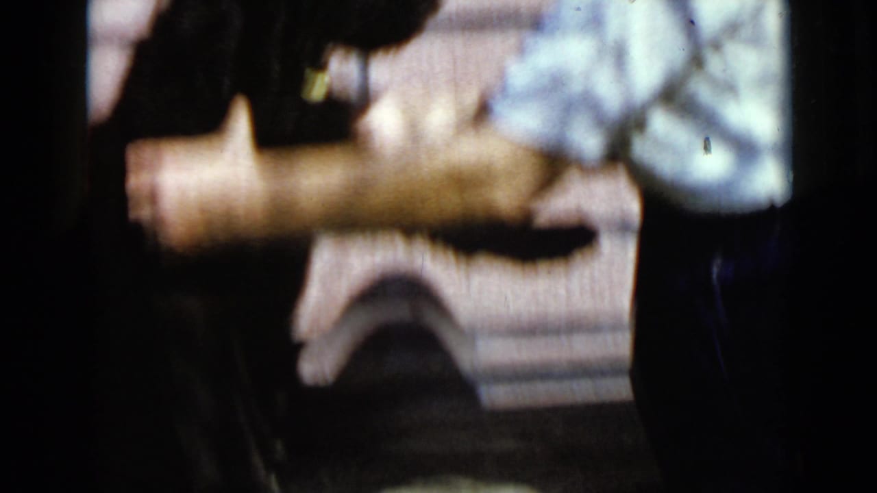 Adult torso and arm near a block wall with a parked vehicle in the background.