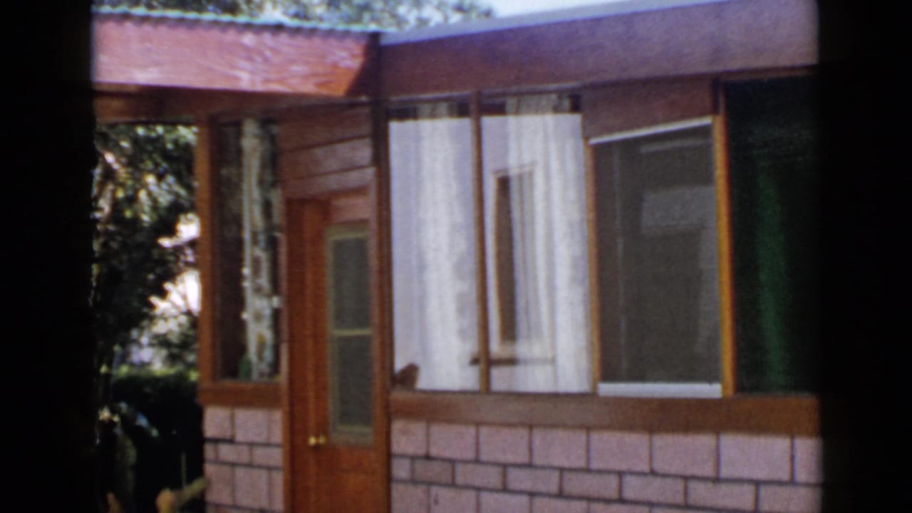 Wood-and-brick house exterior with a glass-paneled door and curtained windows.