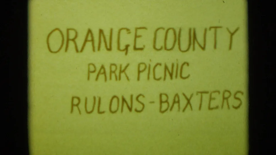 Handwritten home-movie title card reading ORANGE COUNTY PARK PICNIC RULONS-BAXTERS on a pale green background.