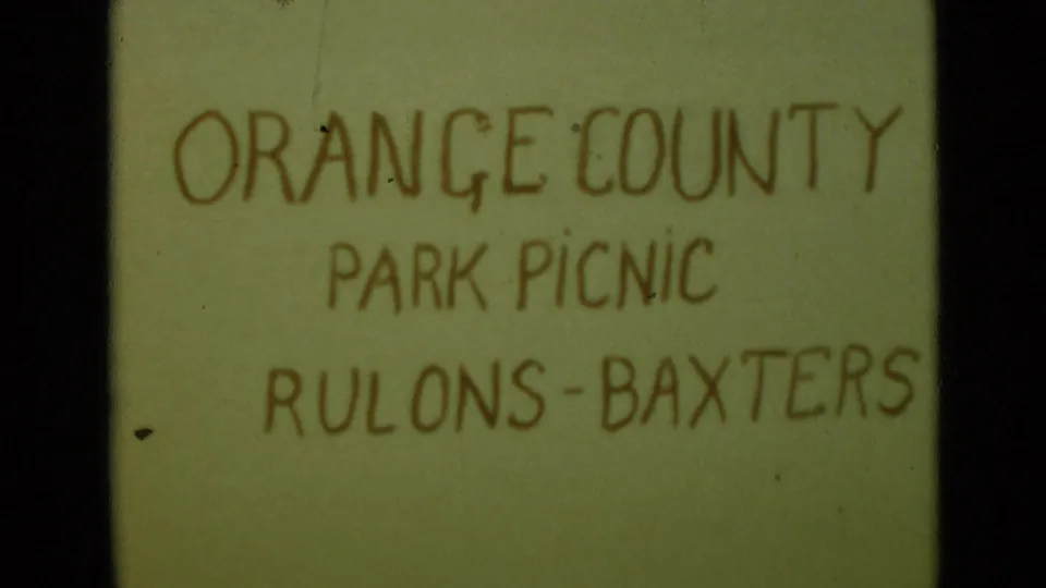 Alternate frame of the handwritten title card reading ORANGE COUNTY PARK PICNIC RULONS-BAXTERS with visible film wear.