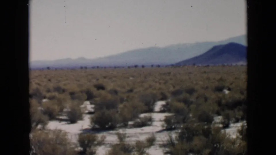 San Diego-area desert view with low scrub, sandy terrain, and hazy mountains in a soft color 8mm frame.