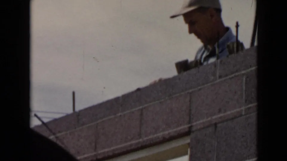 1949 San Diego 8mm frame with a closer view of the mason partly obscured by the concrete block wall as he continues work.