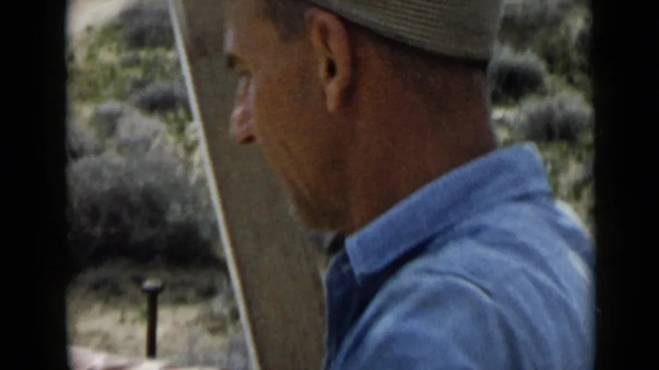 Side view of an adult man in a cap and light blue shirt working outdoors in the 1949 San Diego home-movie clip.