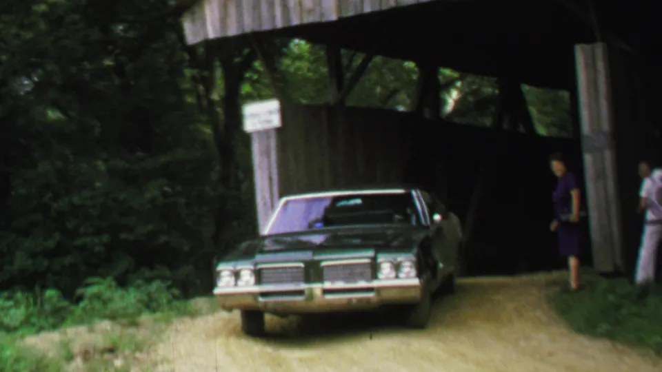 The final frame shows the sedan exiting the covered bridge toward the camera, with adults at the side and wooded vegetation around the road.