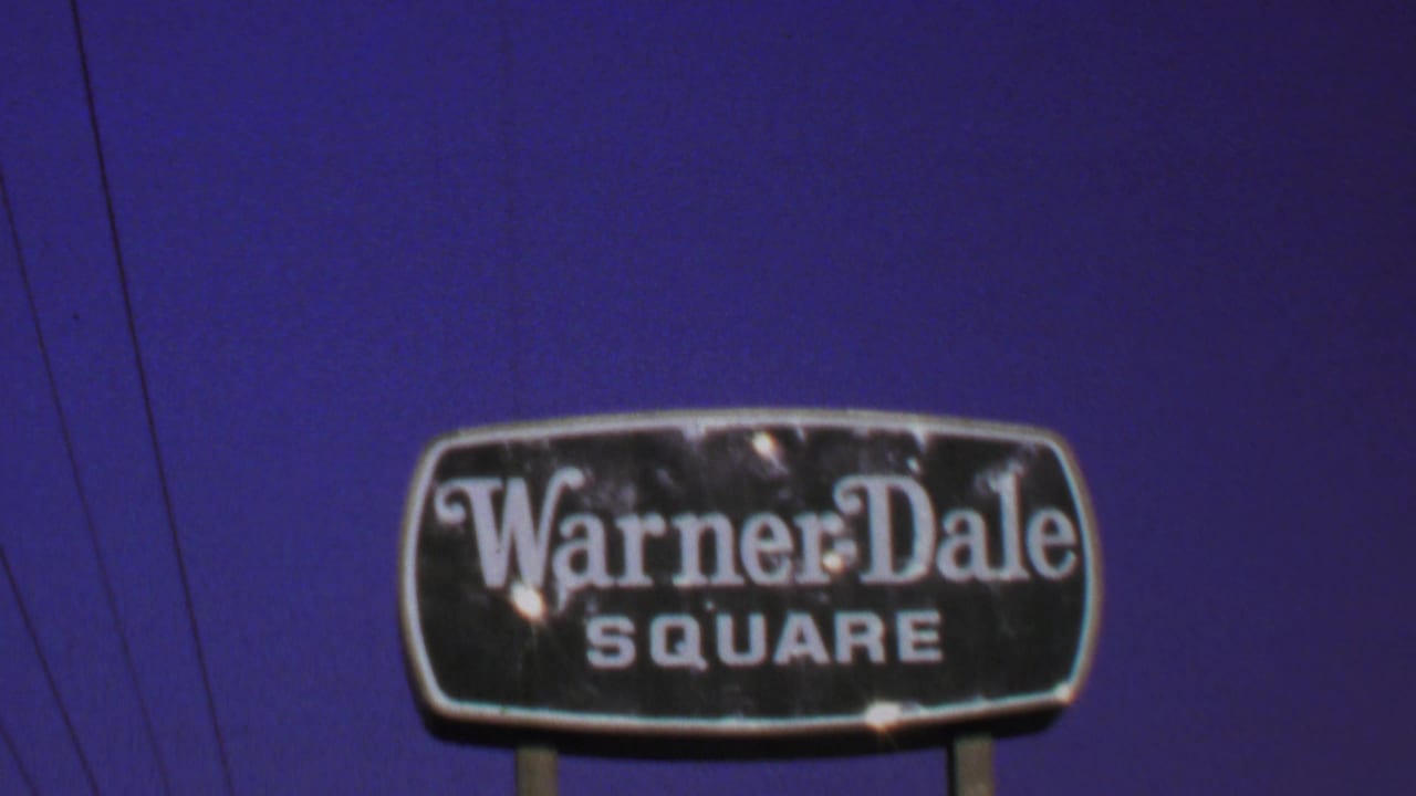 1969 Washington, DC-area frame of a weathered Warner-Dale Square sign on posts, filmed against blue sky with utility wires nearby.