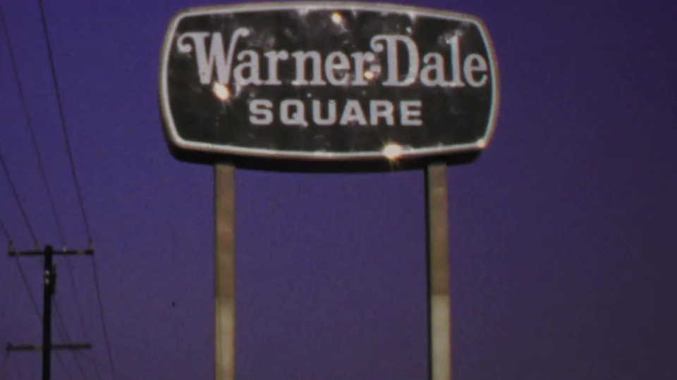 1969 Washington, DC frame showing the Warner Dale Square sign, twin posts, utility pole, wires, and saturated sky.