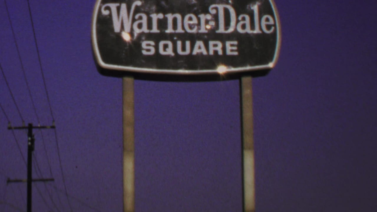 Warner-Dale Square sign lit against a dark purple sky with utility poles nearby.
