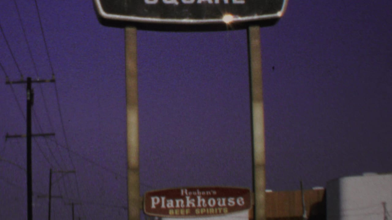 Upper roadside signs and Reuben's Plankhouse billboard partly visible against the night sky.