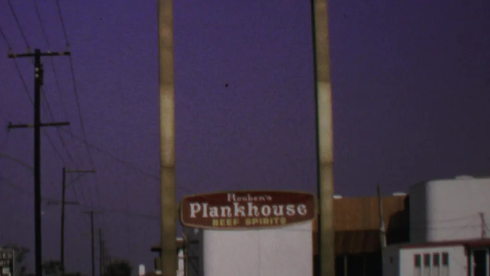 1969 Washington, DC home-movie frame showing Reuben's Plankhouse signage beneath the Warner-Dale Square sign at night.
