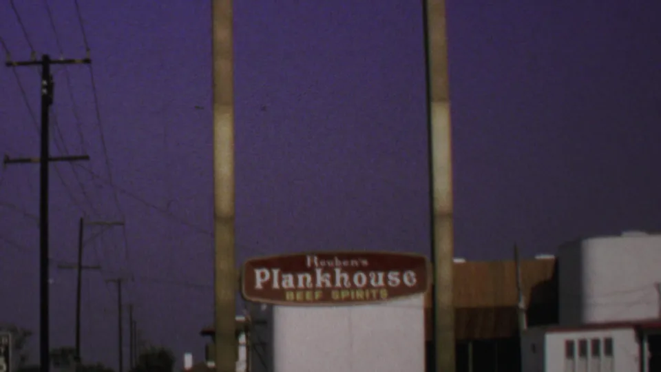 1969 Washington, DC frame holding on the Reuben's Plankhouse sign beside a utility pole, with building details and wires visible.