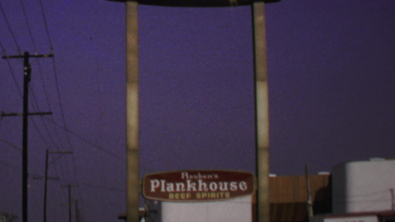 1969 Washington-area 8mm frame with roadside business signage, utility poles, wires, and a deep purple sky.