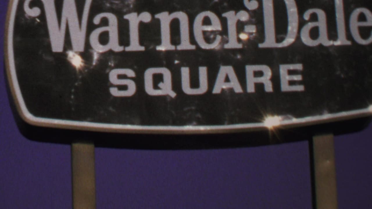 1969 Washington, DC 8mm frame showing a close view of the Warner Dale Square sign with bright glare and film grain.