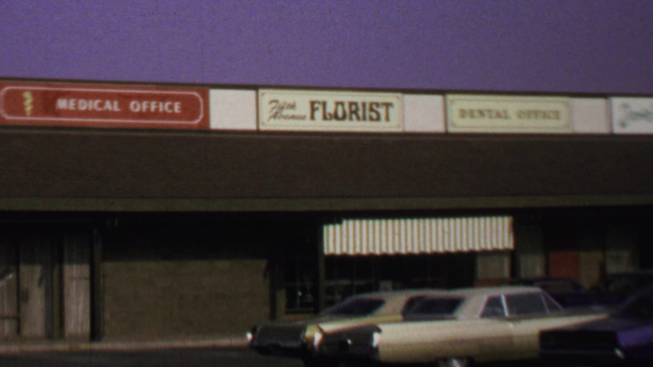 Washington DC storefront view from 1969 showing business signs, striped awnings, and late-1960s cars in front.