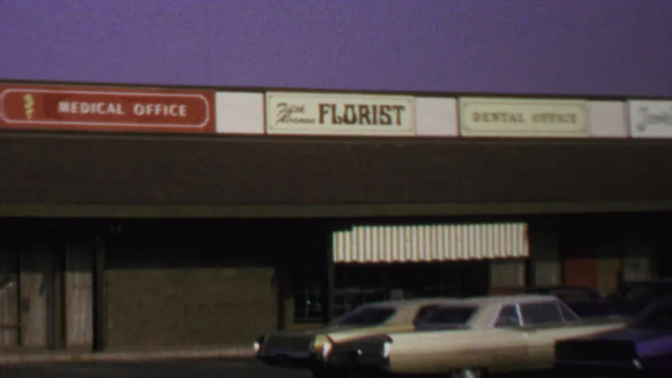 Washington DC storefront view from 1969 showing business signs, striped awnings, and late-1960s cars in front.
