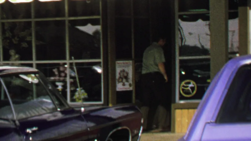 1969 Washington, DC frame showing the man entering the storefront doorway, with large windows and parked cars still visible.