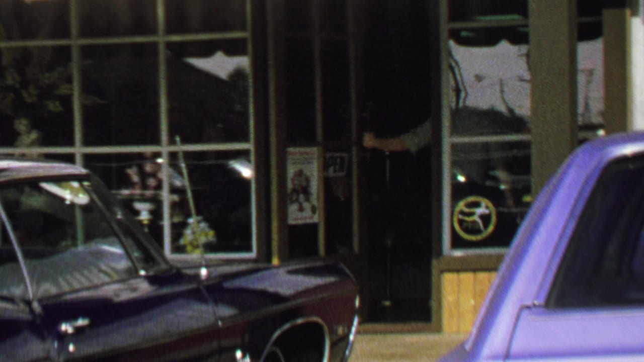 1969 Washington, DC street view with storefront windows, parked cars, and a striped awning edge.