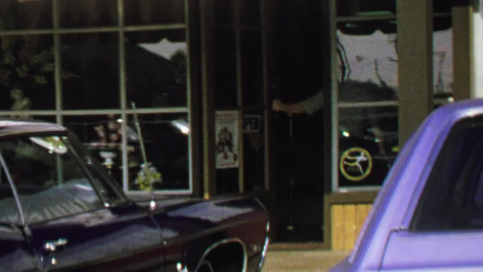 1969 Washington, DC street view with storefront windows, parked cars, and a striped awning edge.
