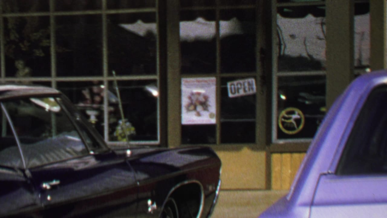 1969 Washington, DC storefront view with classic cars parked outside large windows and OPEN signs.