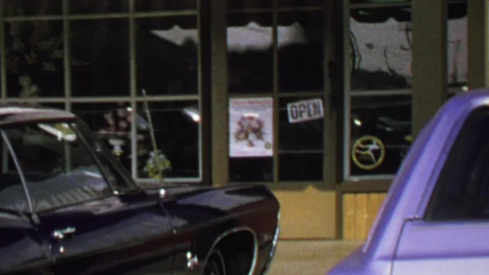 1969 Washington, DC storefront view with classic cars parked outside large windows and OPEN signs.