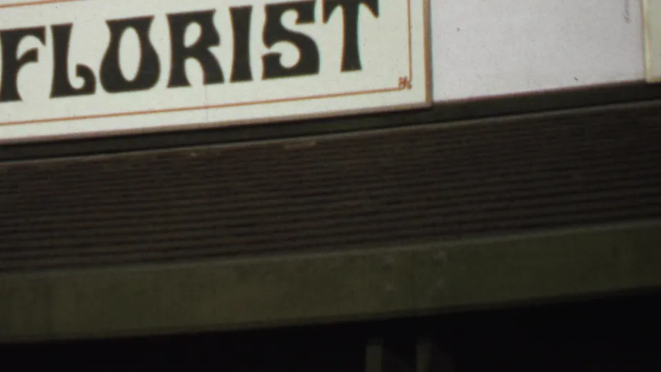 1969 Washington, DC home-movie frame showing part of a cream storefront sign with bold black FLORIST letters.