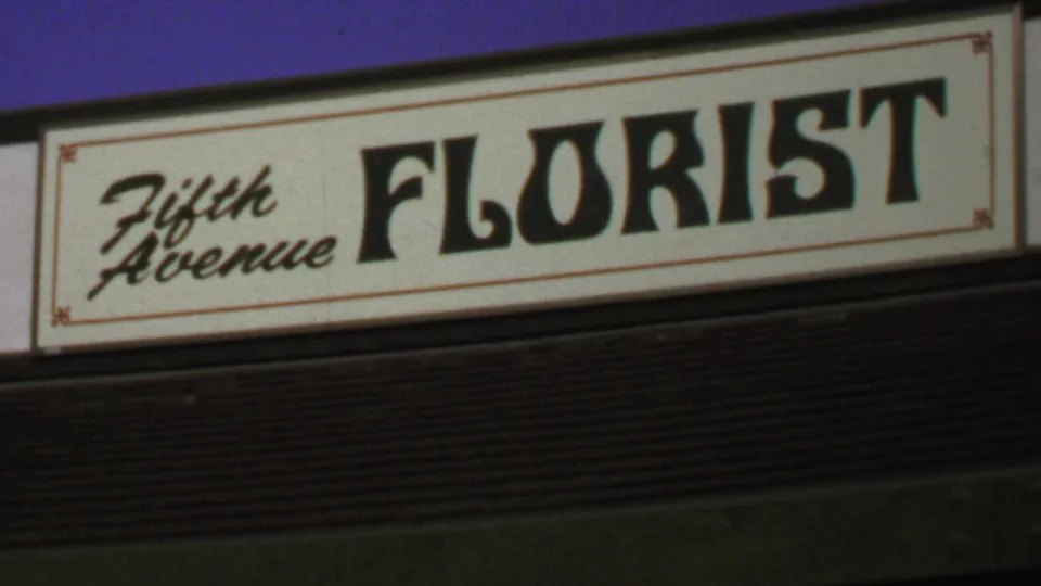 1969 frame of the Fifth Avenue Florist storefront sign, showing cursive-style words beside bold black FLORIST lettering.