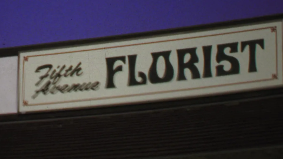The final frame holds an angled view of the Fifth Avenue Florist sign with soft 8mm focus and visible film grain.