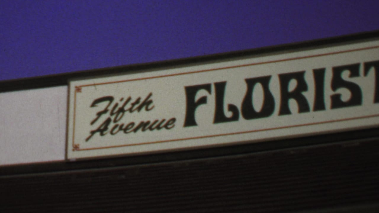 1969 Washington, DC home-movie frame showing a close view of the Fifth Avenue Florist sign with script and bold lettering.