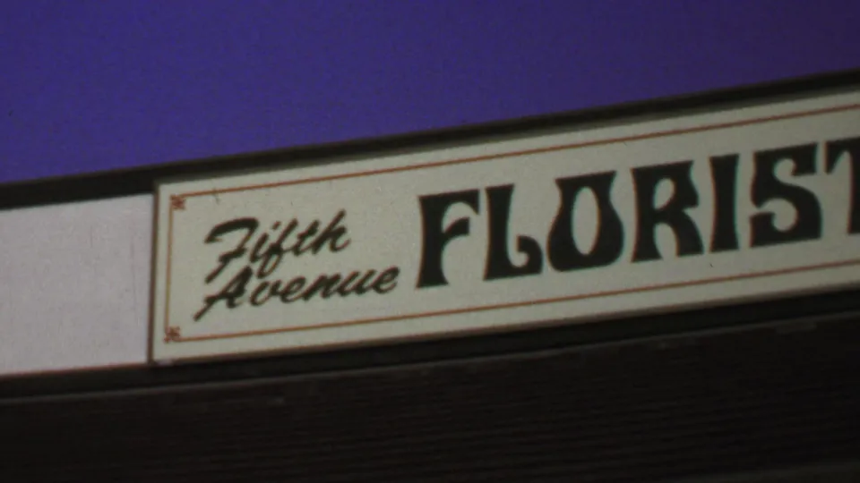 1969 Washington, DC home-movie frame showing a close view of the Fifth Avenue Florist sign with script and bold lettering.