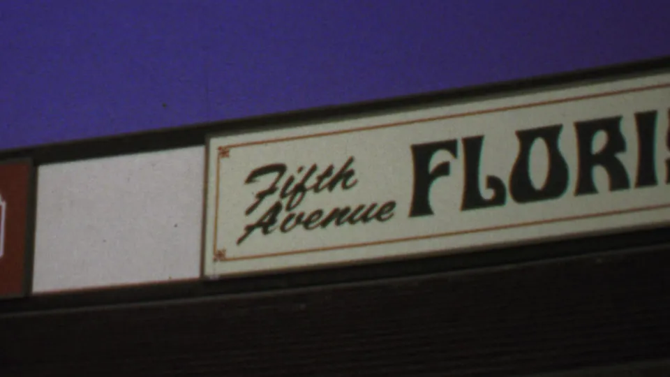 1969 Washington, DC frame with the Fifth Avenue Florist sign, dark facade band, and yellow and white striped awning below.