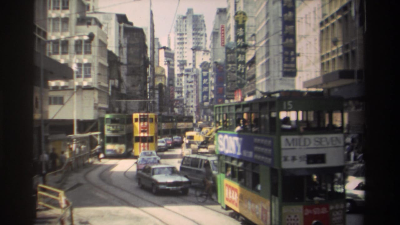 1982 Hong Kong street view with double-decker trams, classic cars, dense commercial buildings, overhead wires, and visible signage.