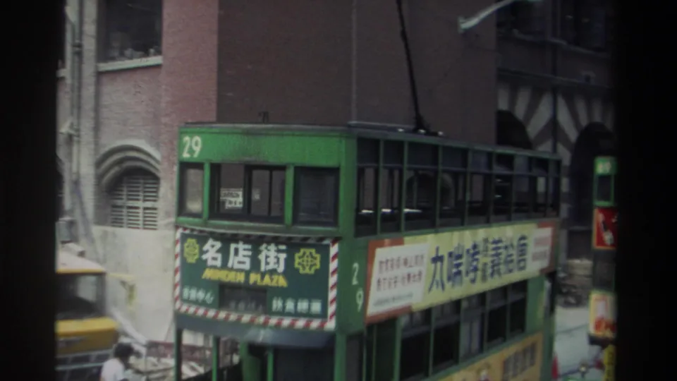 Hong Kong tram marked route 29 passes in front of brick buildings, with a second green tram visible farther along the street.