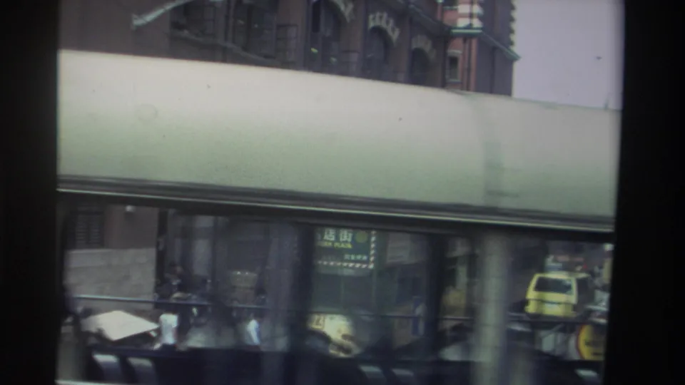 Hong Kong street scene from 1982 showing a bus, covered frontage, vehicles, and partial Chinese signage.
