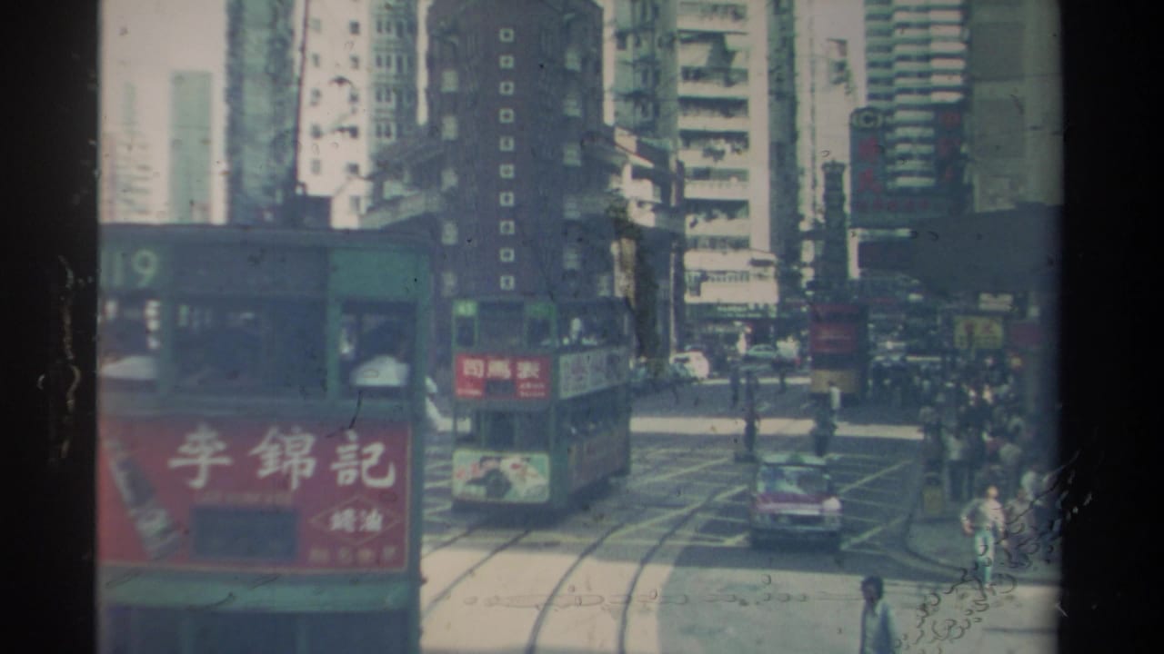 1982 Hong Kong street view with a green double-decker tram, route 119, moving along tracks amid tall buildings and pedestrians.