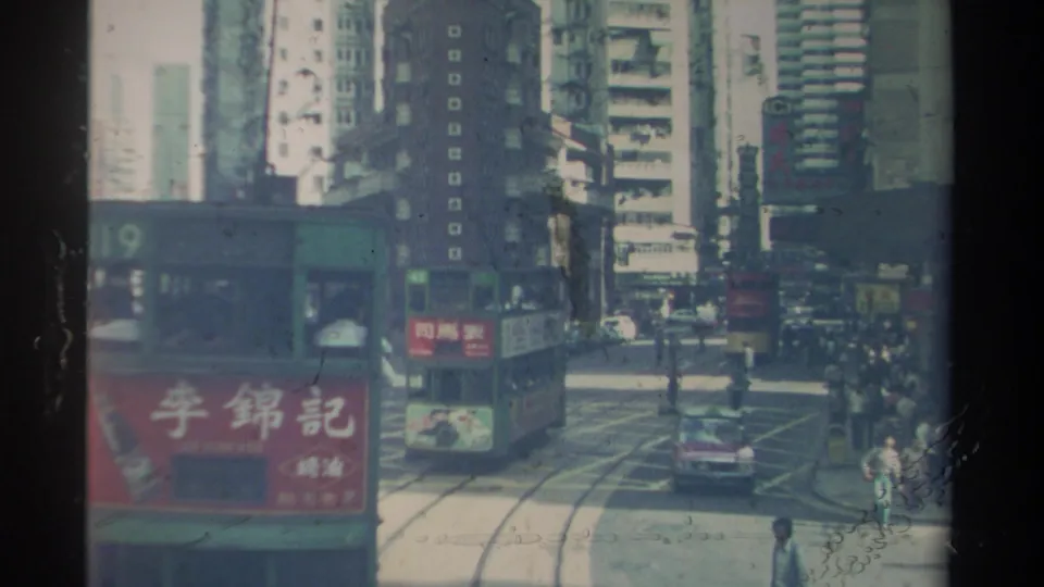 1982 Hong Kong street view with a green double-decker tram, route 119, moving along tracks amid tall buildings and pedestrians.