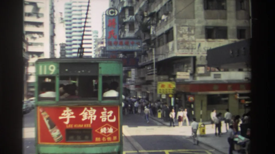 End frame of a 1982 Hong Kong tram ride showing tram 119, Lee Kum Kee advertising, clustered pedestrians, storefronts, and layered street signage.