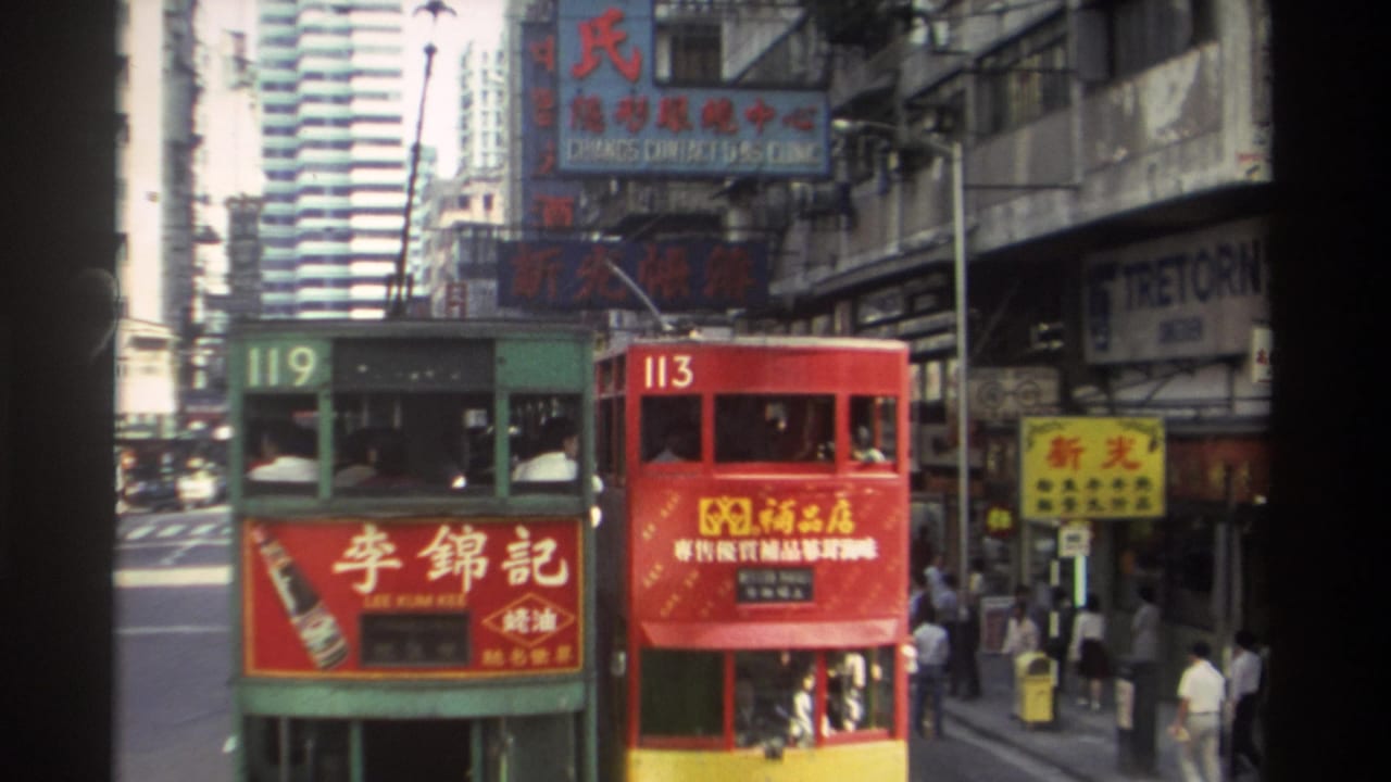 Two double-decker trams on a busy Hong Kong street with Chinese signage and pedestrians nearby.