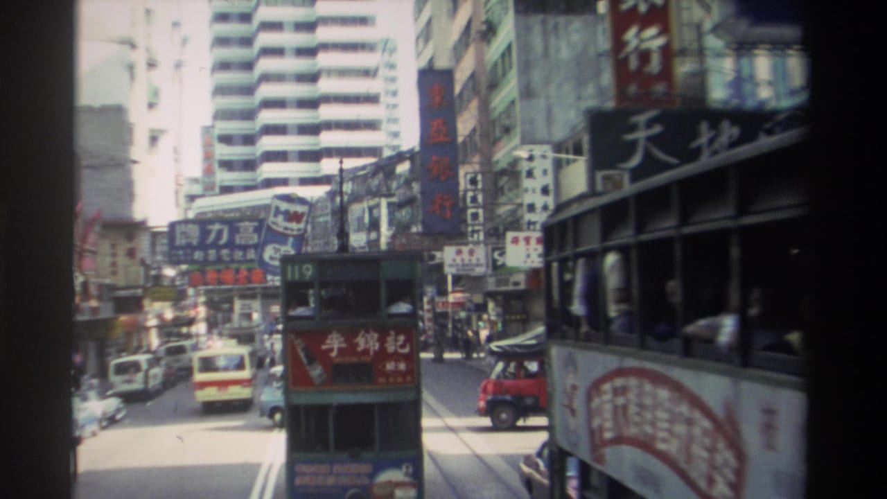 1982 Hong Kong street view with a route 119 double-decker tram ahead, dense traffic, tall buildings, and Chinese-character commercial signs.