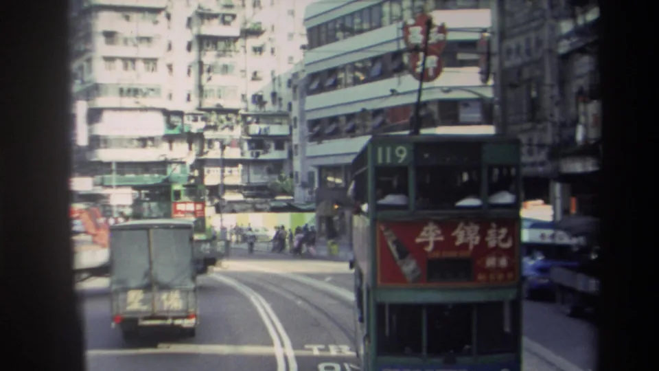 1982 Hong Kong street frame showing a rear-facing truck, route 119 double-decker tram, overhead wires, and commercial signage.
