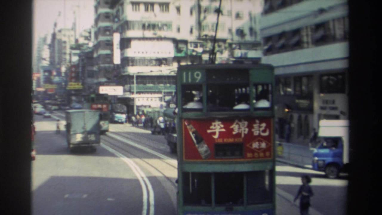Green double-decker tram number 119 with red Lee Kum Kee advertisement panel on a busy Hong Kong street, dense multi-storey buildings and Chinese signage on both sides.