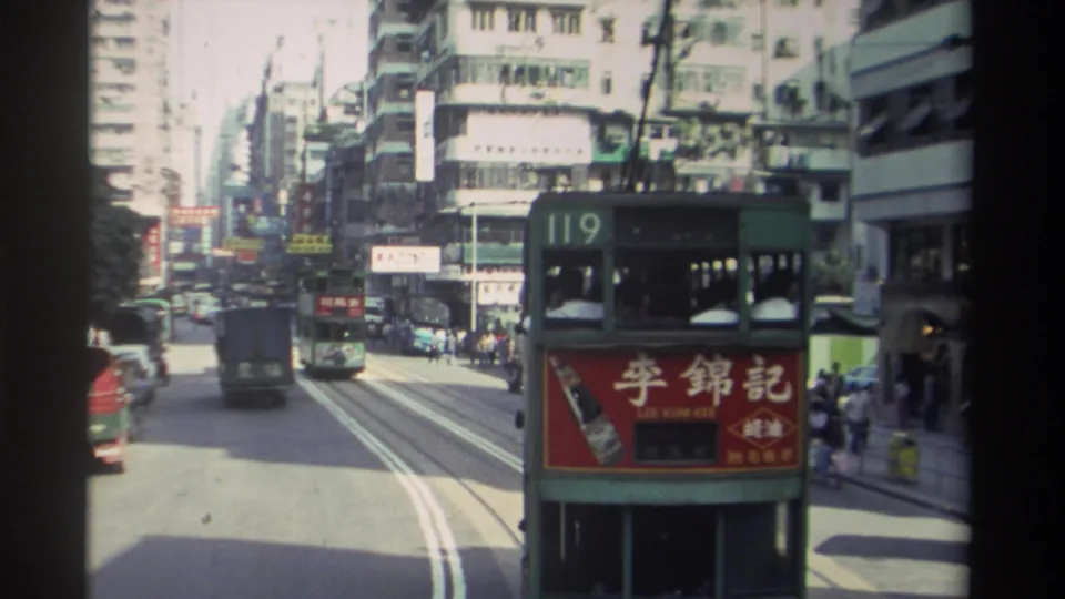 Route-119 Hong Kong tram with Lee Kum Kee rear panel advertisement travelling through a dense urban canyon, circa 1982, 8mm footage shot from a moving vehicle.