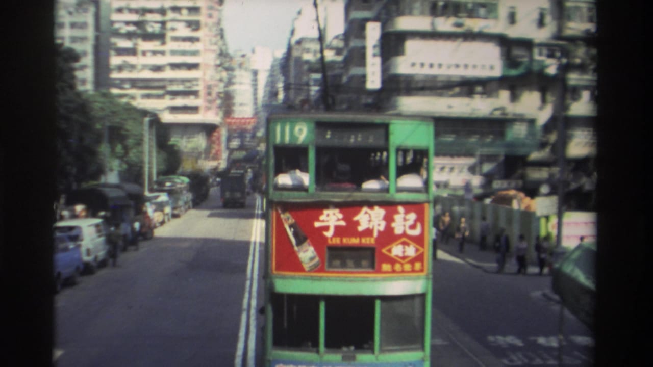Hong Kong tram route 119 moving along a busy urban street, circa 1982, with Lee Kum Kee advertisement, parked vehicles, and densely packed tower blocks behind.