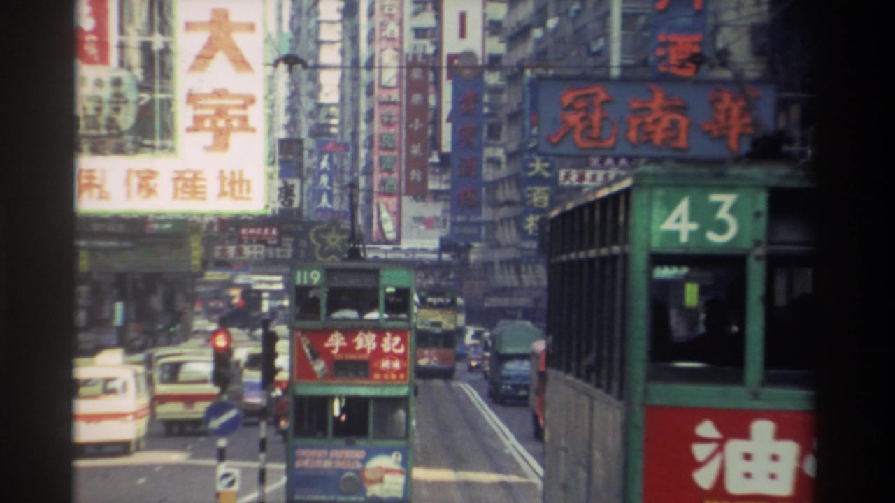 Green double-decker tram numbered 43 on a busy Hong Kong street lined with dense Chinese-language building signage.