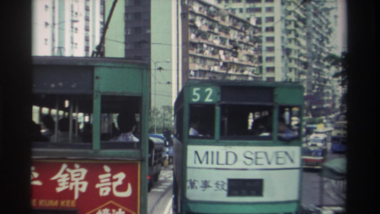 Closer view of route 52 green double-decker tram with 'MILD SEVEN' advertisement panel, dense apartment towers behind.