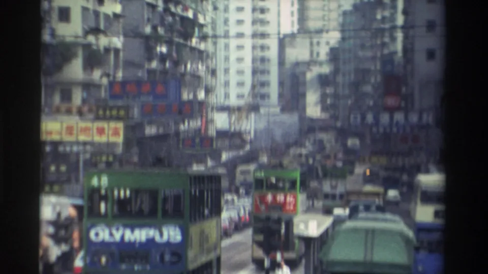 Green double-decker buses, one displaying route 48 with a prominent Olympus advertisement, move through dense 1982 Hong Kong traffic below a canopy of Chinese-character commercial signs.