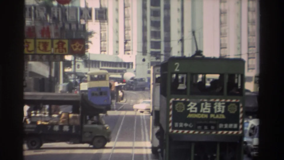 A green delivery truck in the foreground and the route-2 tram (Minden Plaza) share the tram corridor in a 1982 Hong Kong street lined with Chinese-language commercial signs and tower blocks.