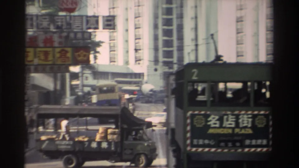 The route-2 Minden Plaza tram and surrounding street traffic, including a delivery truck with visible cargo, captured in 1982 Hong Kong amid dense Chinese commercial signage and high-rise buildings.