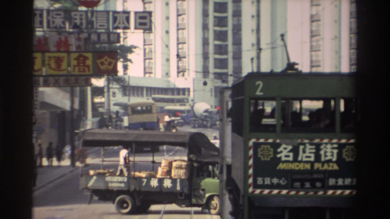 Street-level view of a Hong Kong tram numbered 2 bearing a bilingual Minden Plaza destination board, with a loaded flatbed truck and dense Chinese commercial signs overhead, circa 1982.